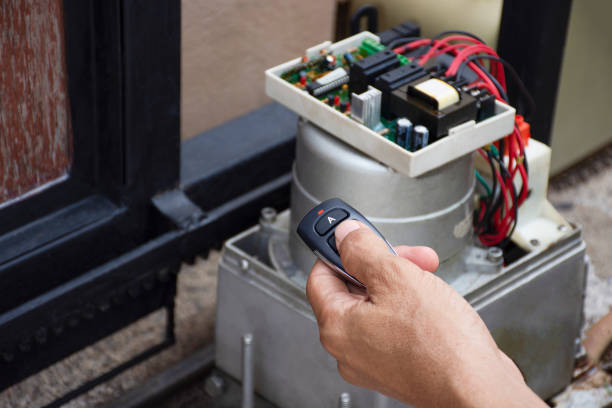 Technician man hand holding remote control, testing and checking the functional of motor gear automatic gate. Maintenance concept.