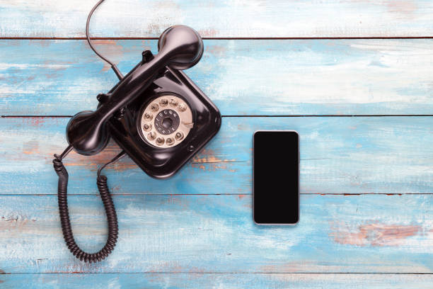 Old telephone and mobile phone on a blue wooden board Old telephone and mobile phone on a blue wooden board